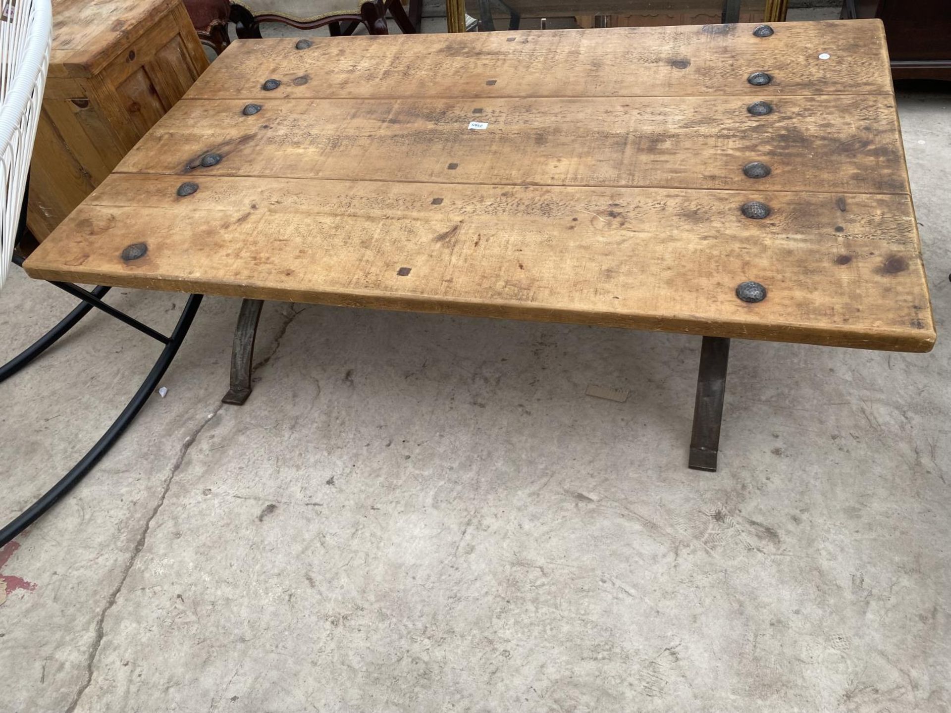 A RUSTIC THREE PLANK LOW TABLE ON METALWARE BASE WITH TWELVE STUDS, 60X35"