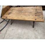 A RUSTIC THREE PLANK LOW TABLE ON METALWARE BASE WITH TWELVE STUDS, 60X35"