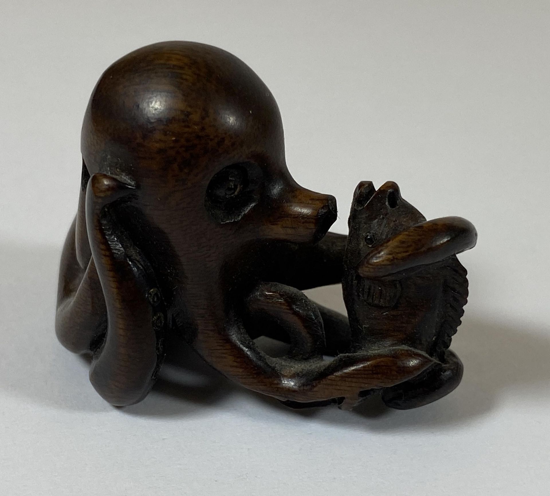 AN ORIENTAL NETSUKE OF AN OCTUPUS AND FISH, SIGNED WITH MOTHER OF PEARL MAKERS MARK, HEIGHT 3.5CM