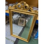 AN ORNATE GILT FRAMED MIRROR WITH RIBBON DESIGN TOP