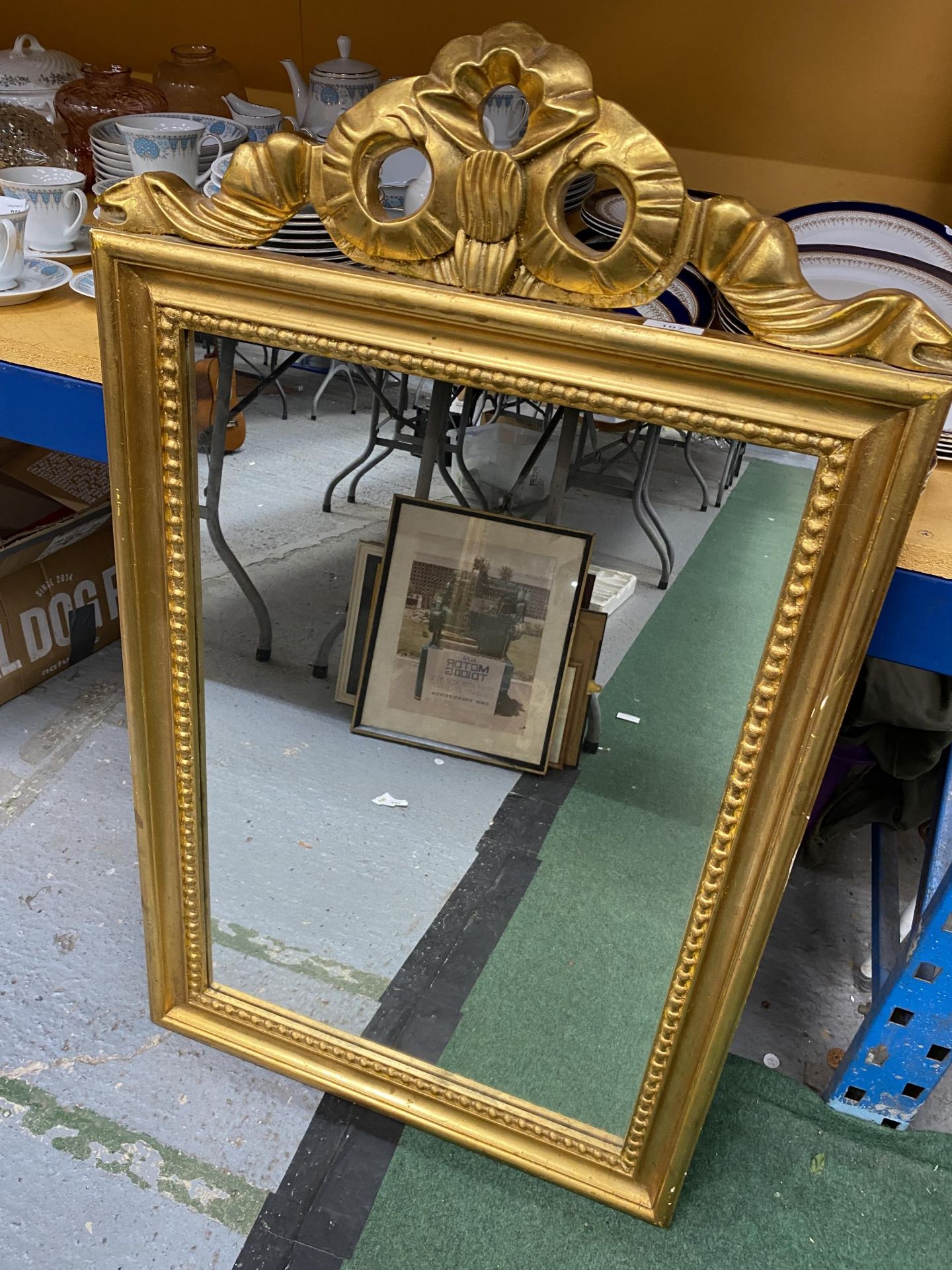 AN ORNATE GILT FRAMED MIRROR WITH RIBBON DESIGN TOP