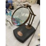 A BRASS MAGNIFYING GLASS ON A WOODEN BASE