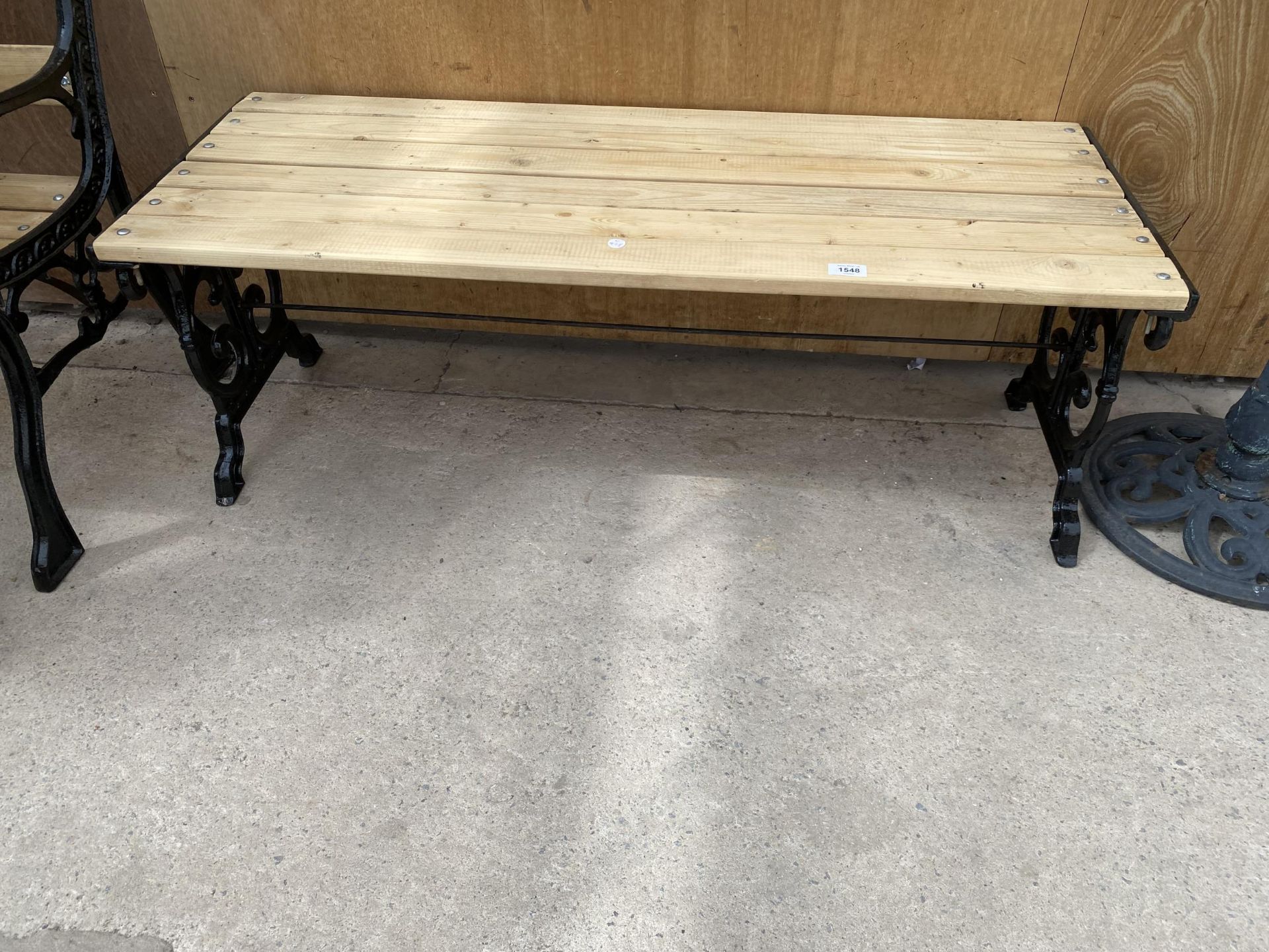 A WOODEN SLATTED TABLE WITH CAST IRON BENCH ENDS