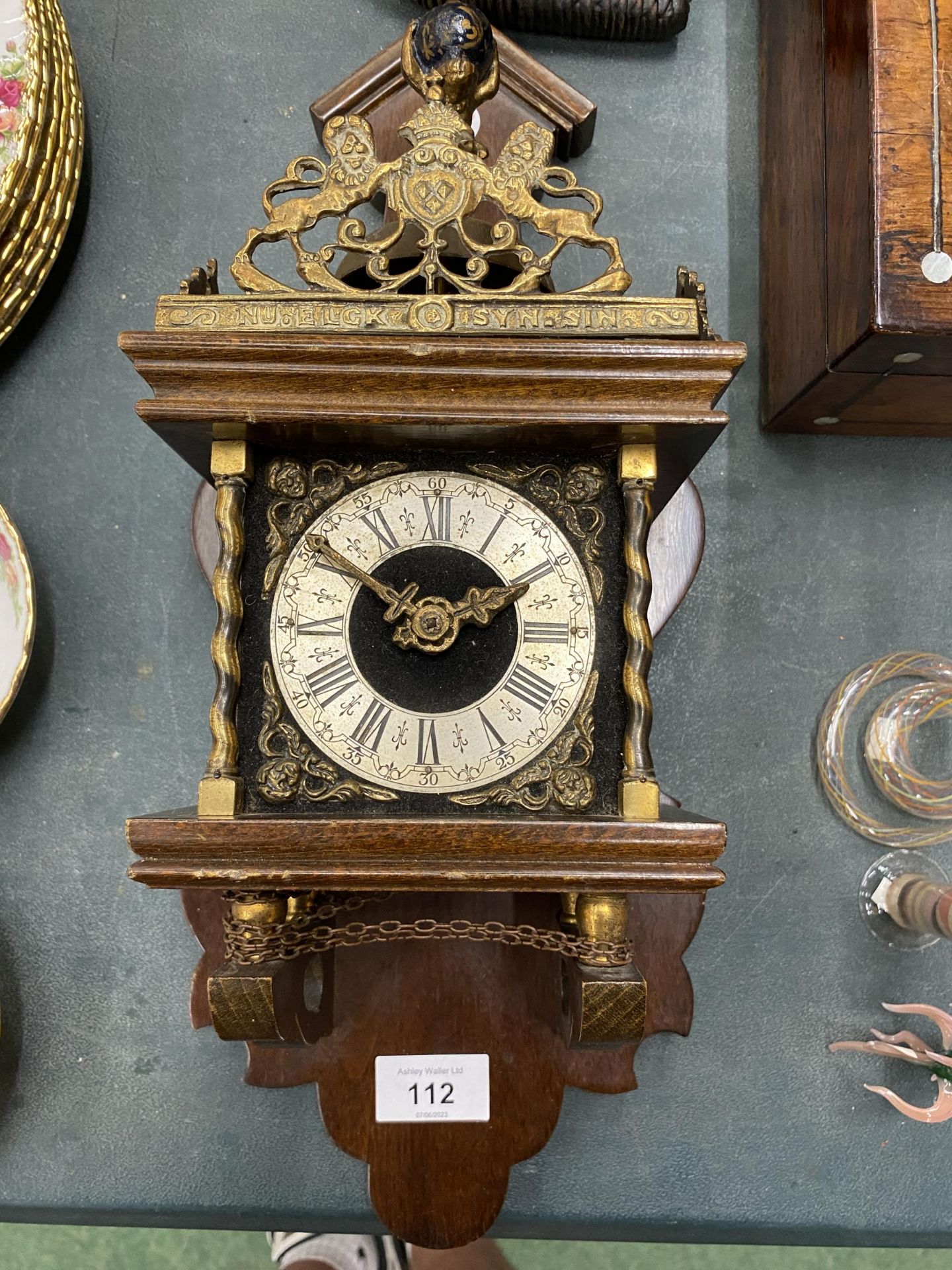 A VINTAGE MAHOGANY CASED WALL CLOCK WITH BRASS DECORATION - LACKING KEY, AND WEIGHTS