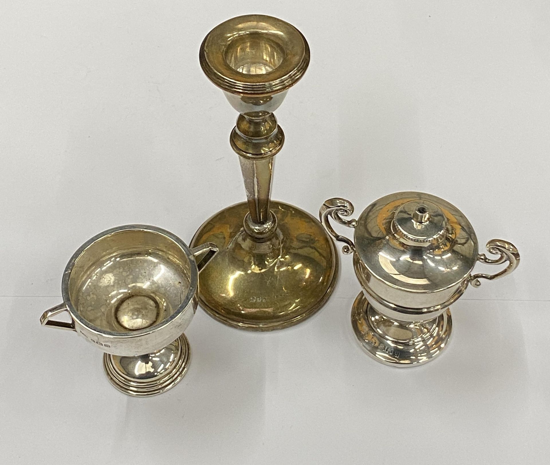 A GROUP OF THREE HALLMARKED SILVER ITEMS COMPRISING A WEIGHTED CANDLESTICK, LIGHTER AND TWIN HANDLED