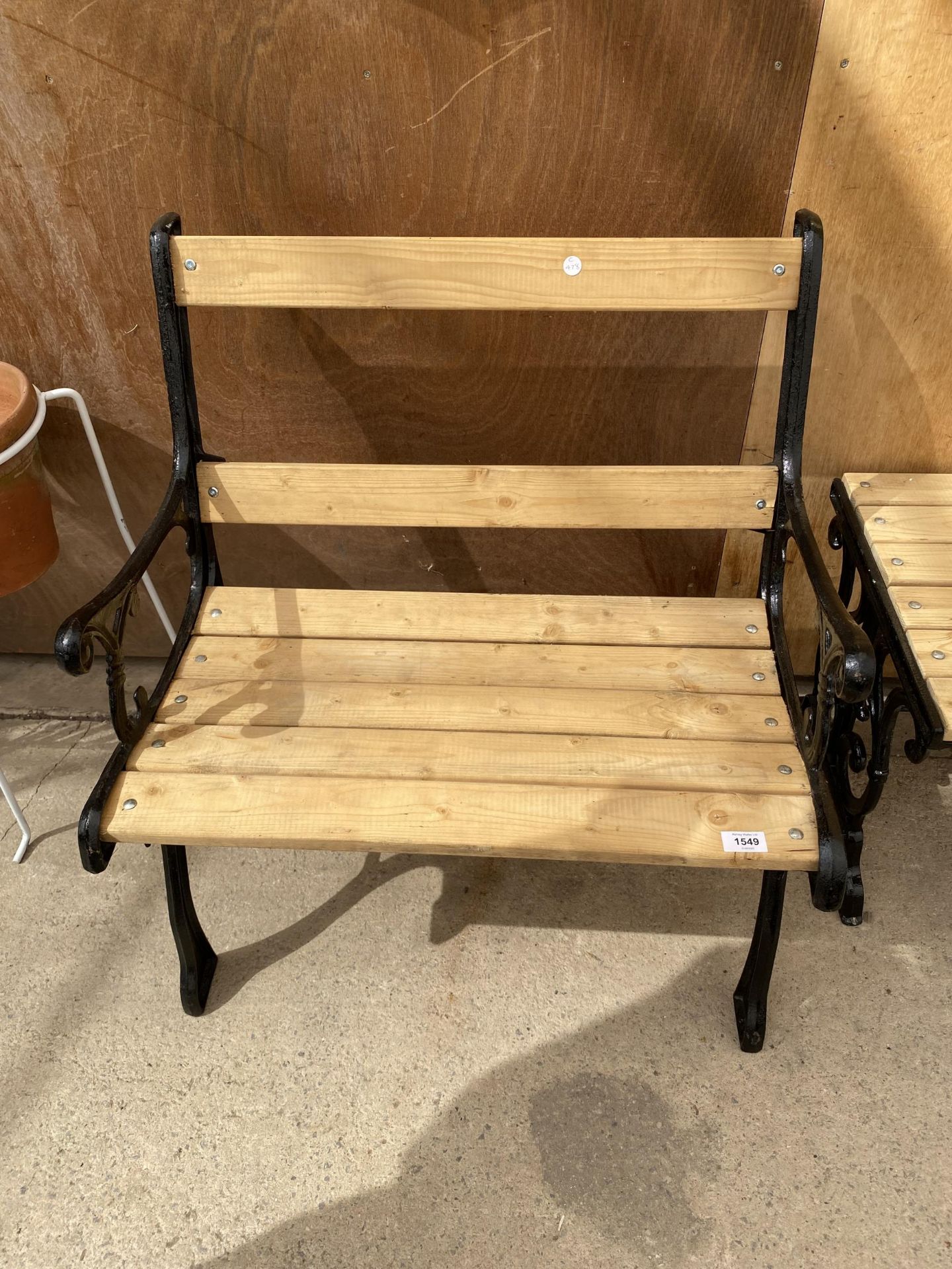 A WOODEN SLATTED WIDE CHAIR WITH CAST IRON ENDS