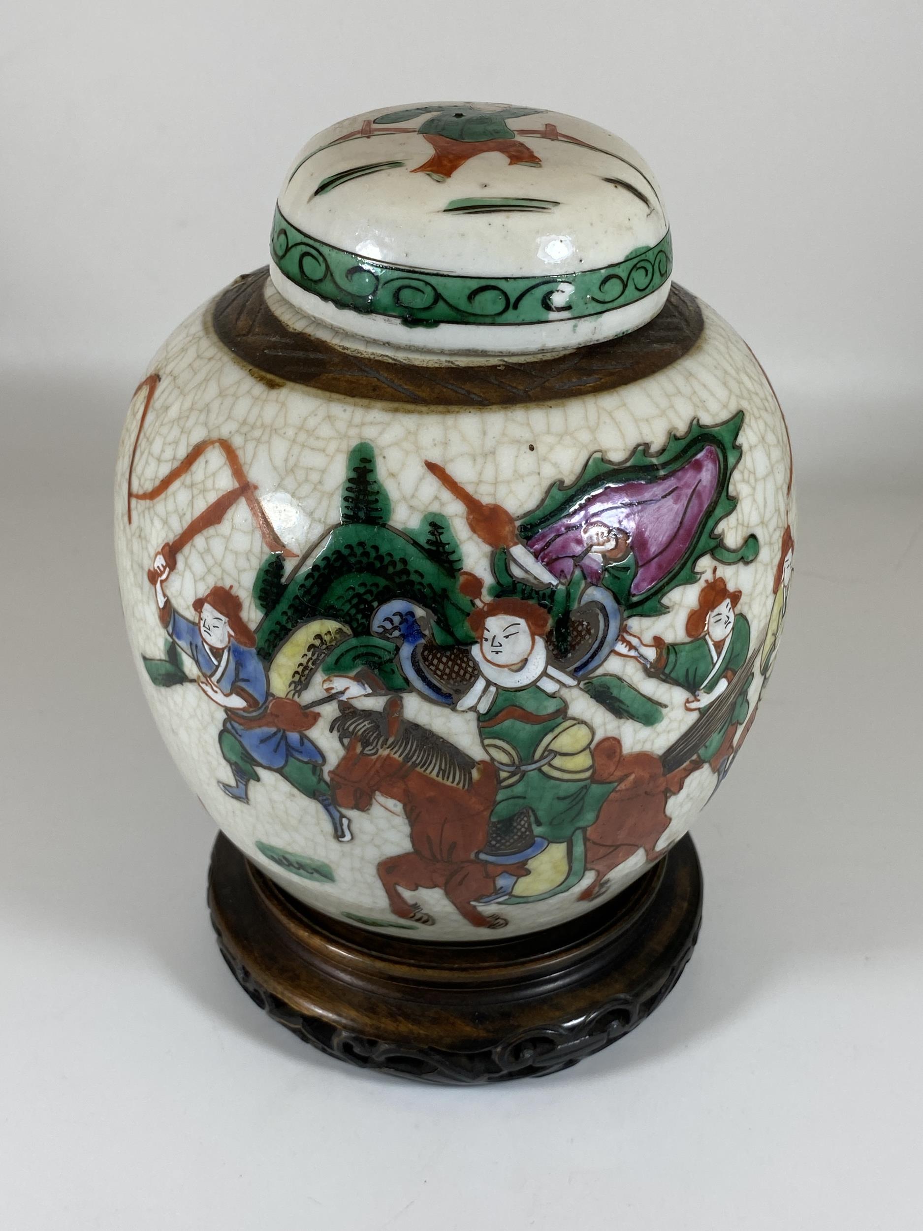 A LATE 19TH/EARLY 20TH CENTURY CHINESE CRACKLE GLAZE WARRIOR DESIGN GINGER JAR ON CARVED WOODEN