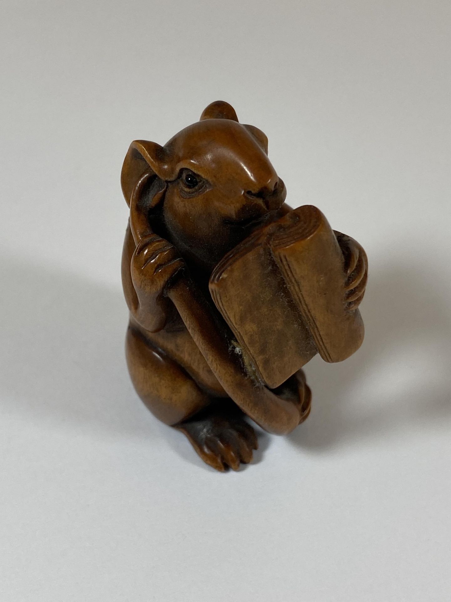 AN ORIENTAL NETSUKE OF A RABBIT READING, HAND A/F, SIGNED TO BASE, HEIGHT 4.5CM