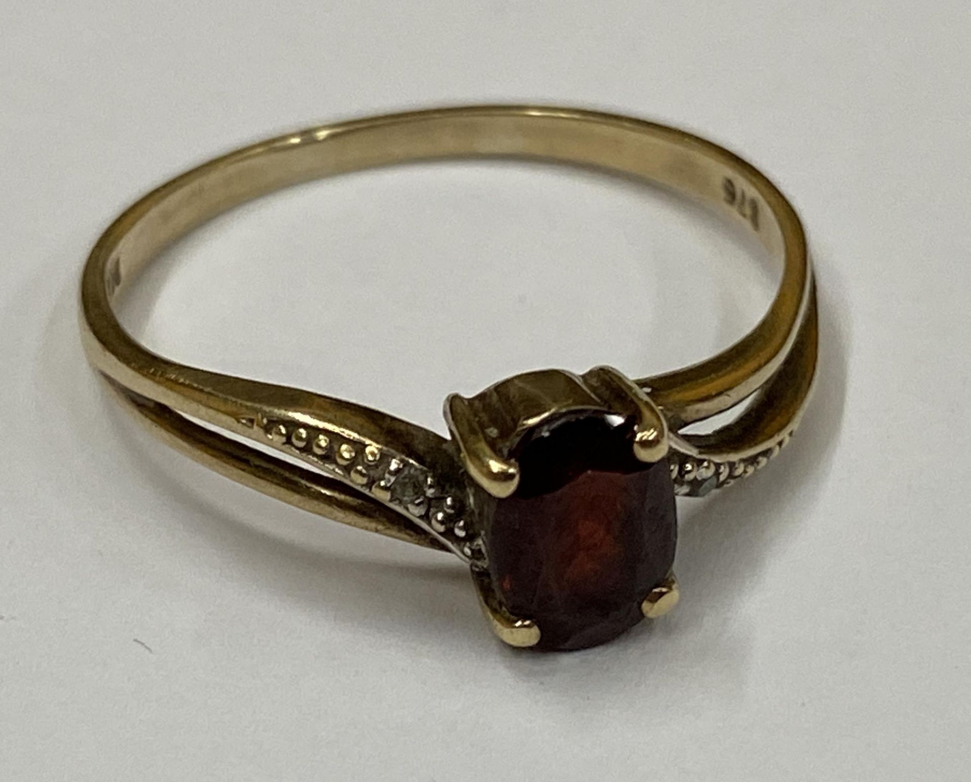 A 9CT YELLOW GOLD RING WITH GARNET AND DIAMOND SHOULDERS, WEIGHT 1.9G