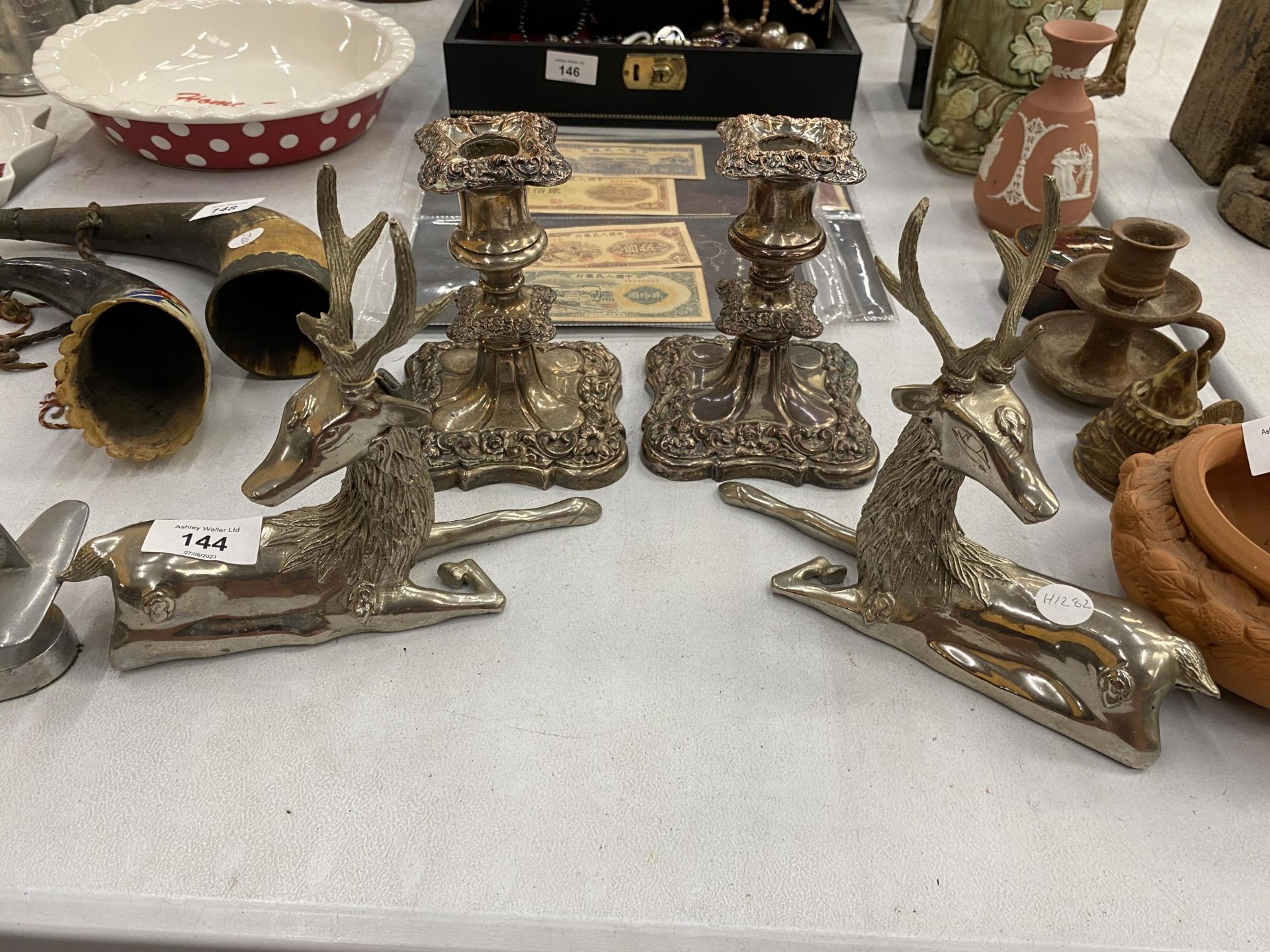 A PAIR OF HEAVY WHITE METAL STAG ORNAMENTS AND A PAIR OF PLATED CANDLESTICKS