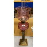 A VINTAGE BRASS CORNINTHIAN COLUMN OIL LAMP WITH CRANBERRY GLASS RESERVOIR, HEIGHT 72CM