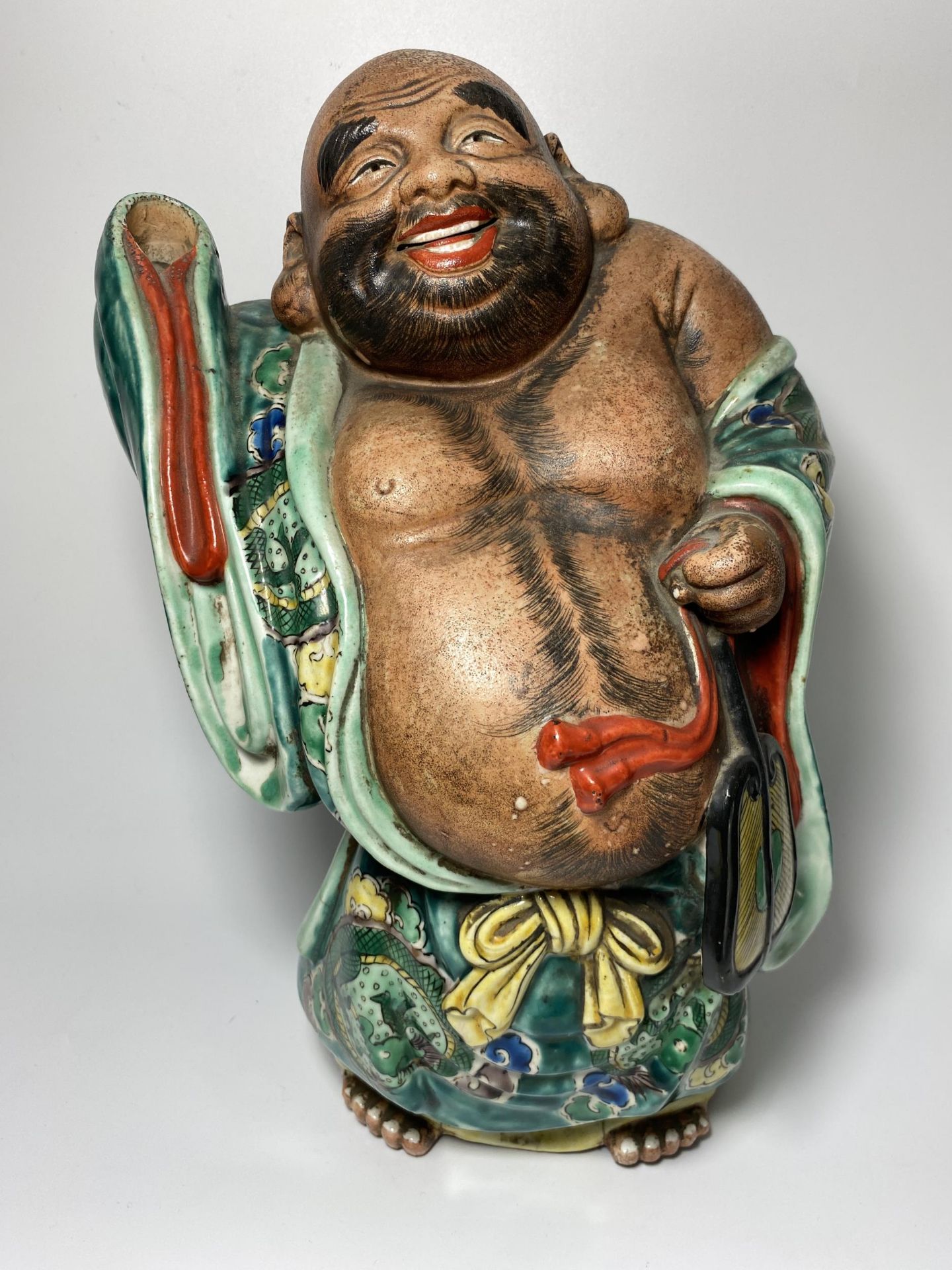 A LARGE JAPANESE MEIJI PERIOD (1868-1912) POTTERY MODEL OF HOTEI WEARING CHINESE DRAGON DESIGN ROBE,
