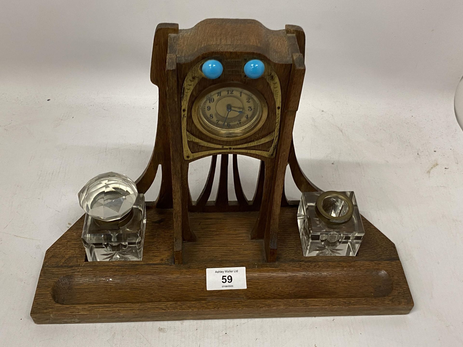 AN ARTS AND CRAFTS WOODEN CLOCK WITH INSET INKWELLS