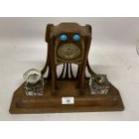 AN ARTS AND CRAFTS WOODEN CLOCK WITH INSET INKWELLS