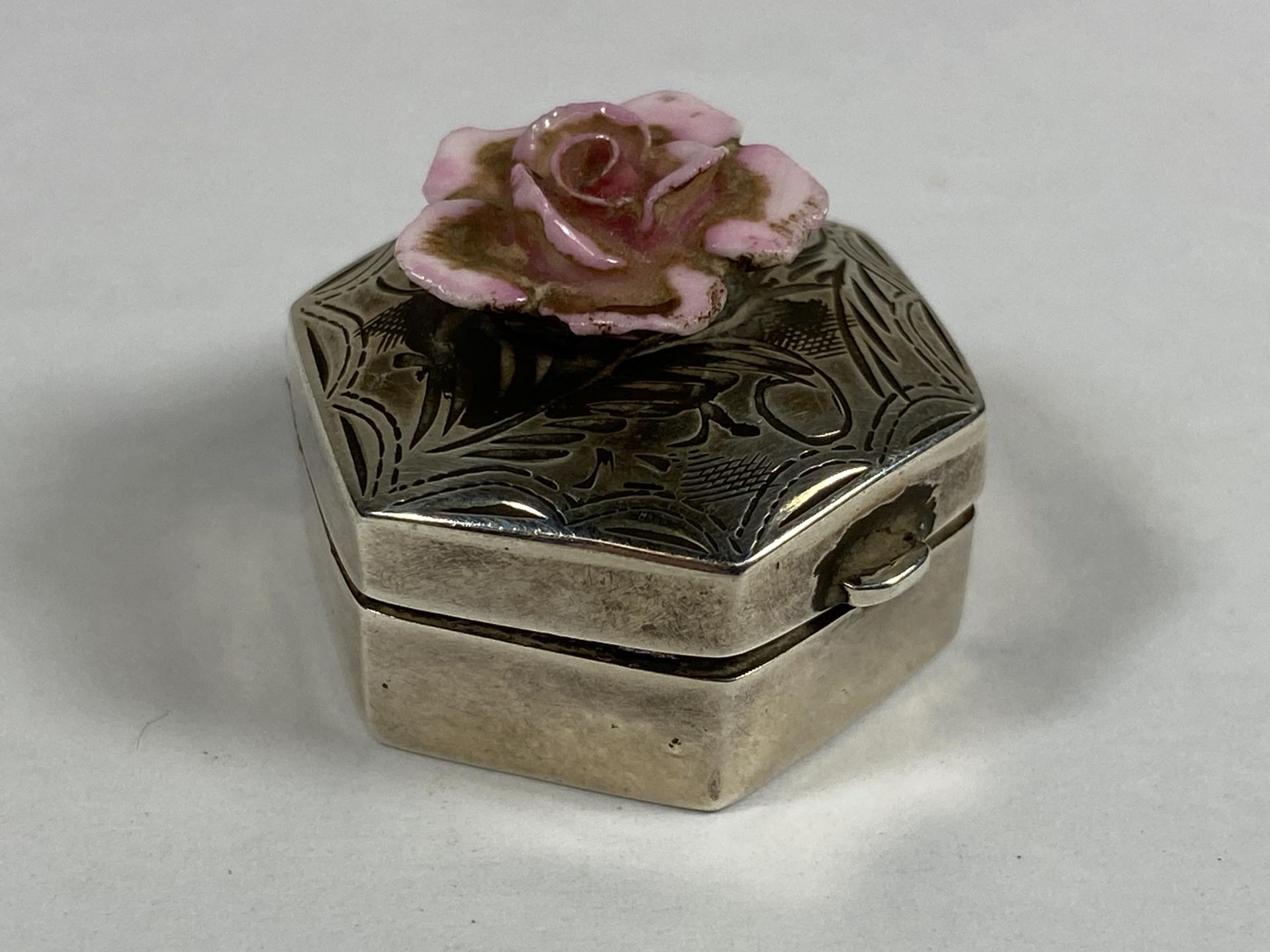 A MINIATURE HALLMARKED SILVER PILL BOX WITH FLORAL DESIGN TOP