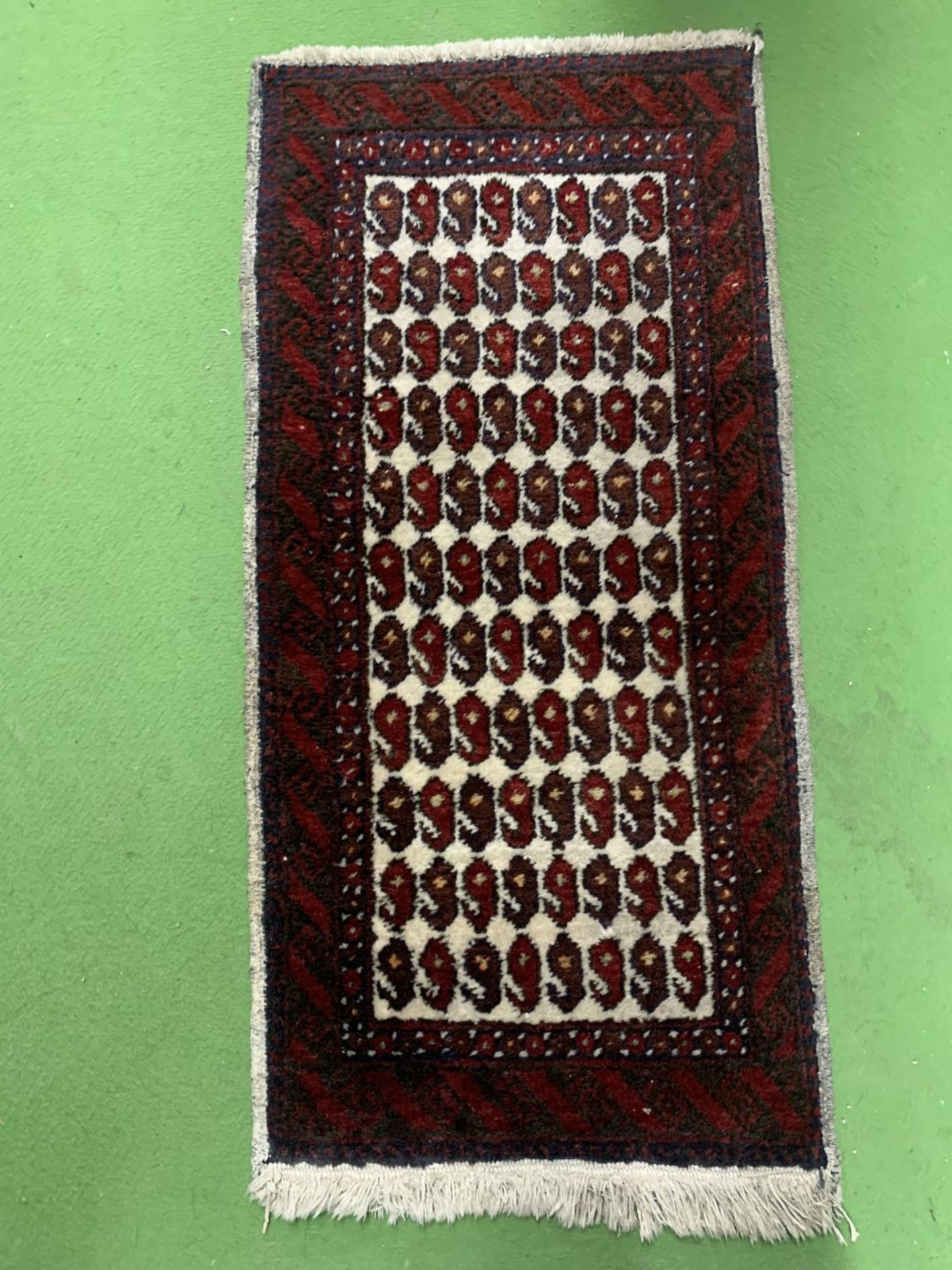 A SMALL WOOLLEN RUG 88CM X 43CM