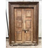A PAIR OF INDIAN HARDWOOD PANELLED DOORS WITH BRASS FITTINGS + CARVED CORNICE, 84 X 58" INCLUDING