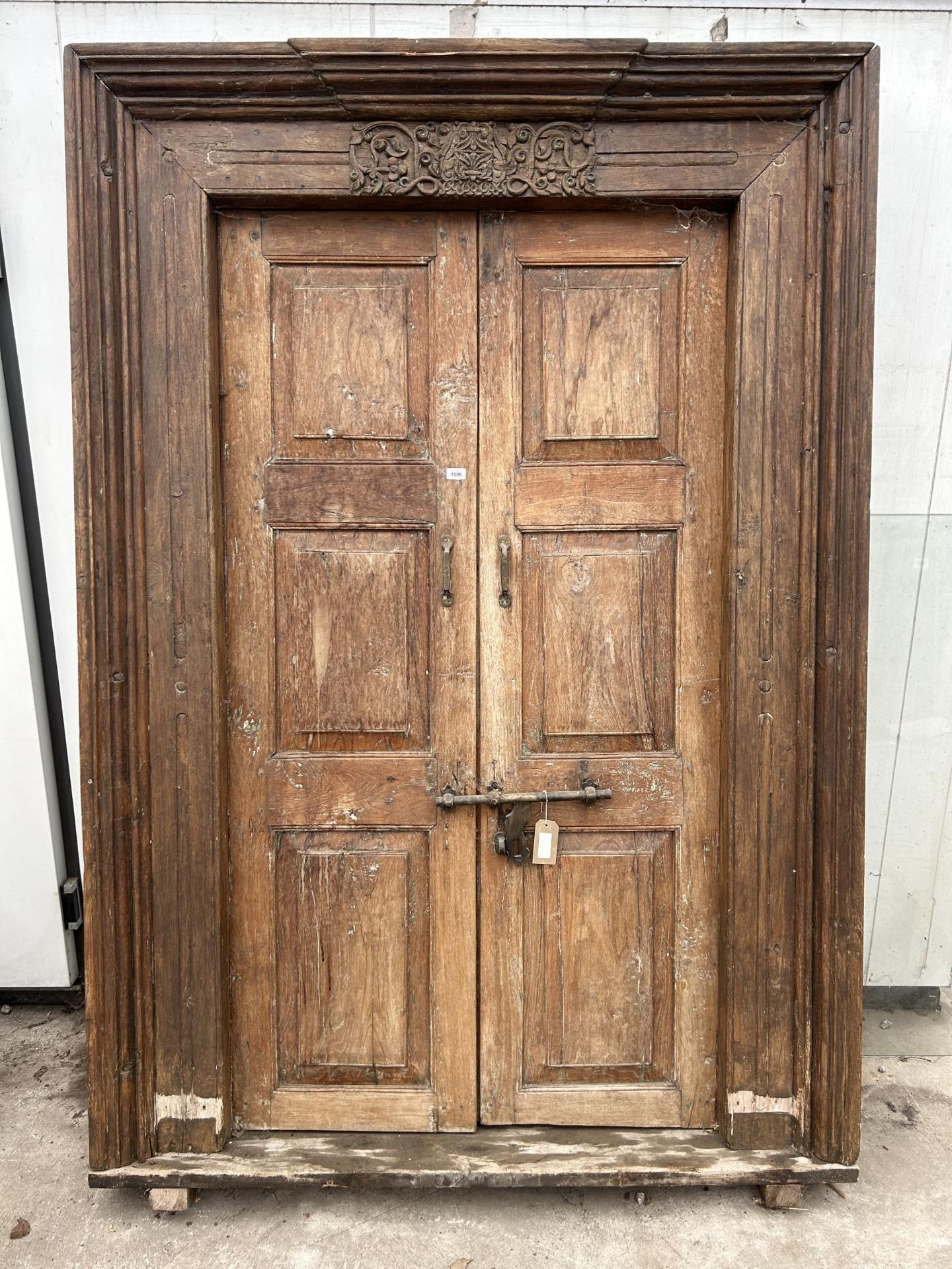 A PAIR OF INDIAN HARDWOOD PANELLED DOORS WITH BRASS FITTINGS + CARVED CORNICE, 84 X 58" INCLUDING