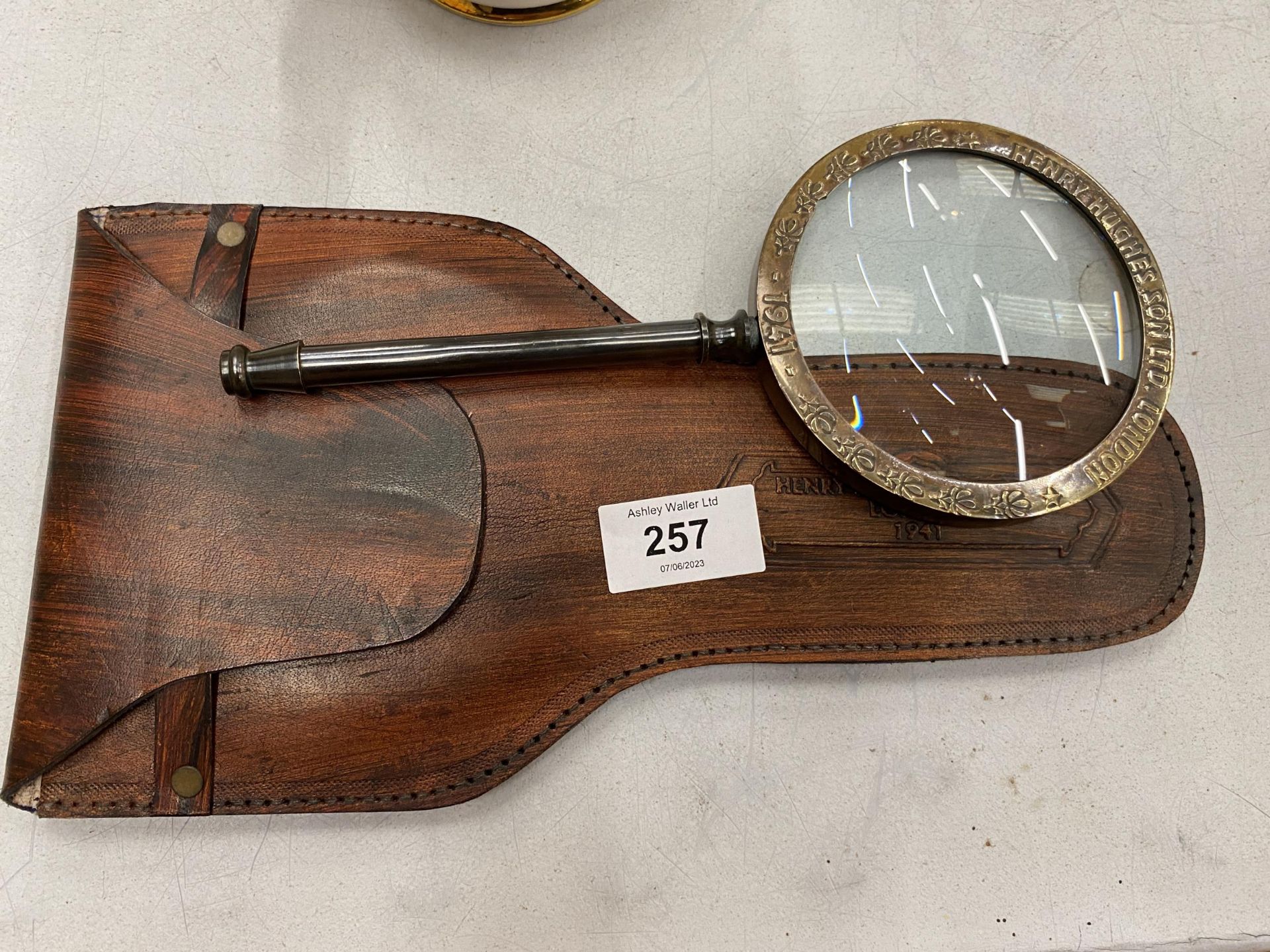 A BRASS MAGNIFYING GLASS IN A LEATHER POUCH