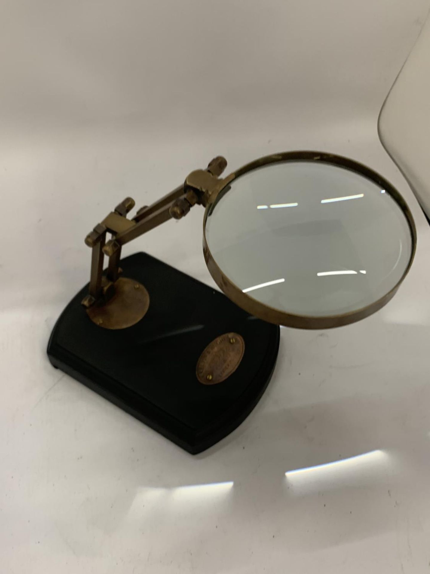 A BRASS MAGNIFYING GLASS ON A WOODEN BASE