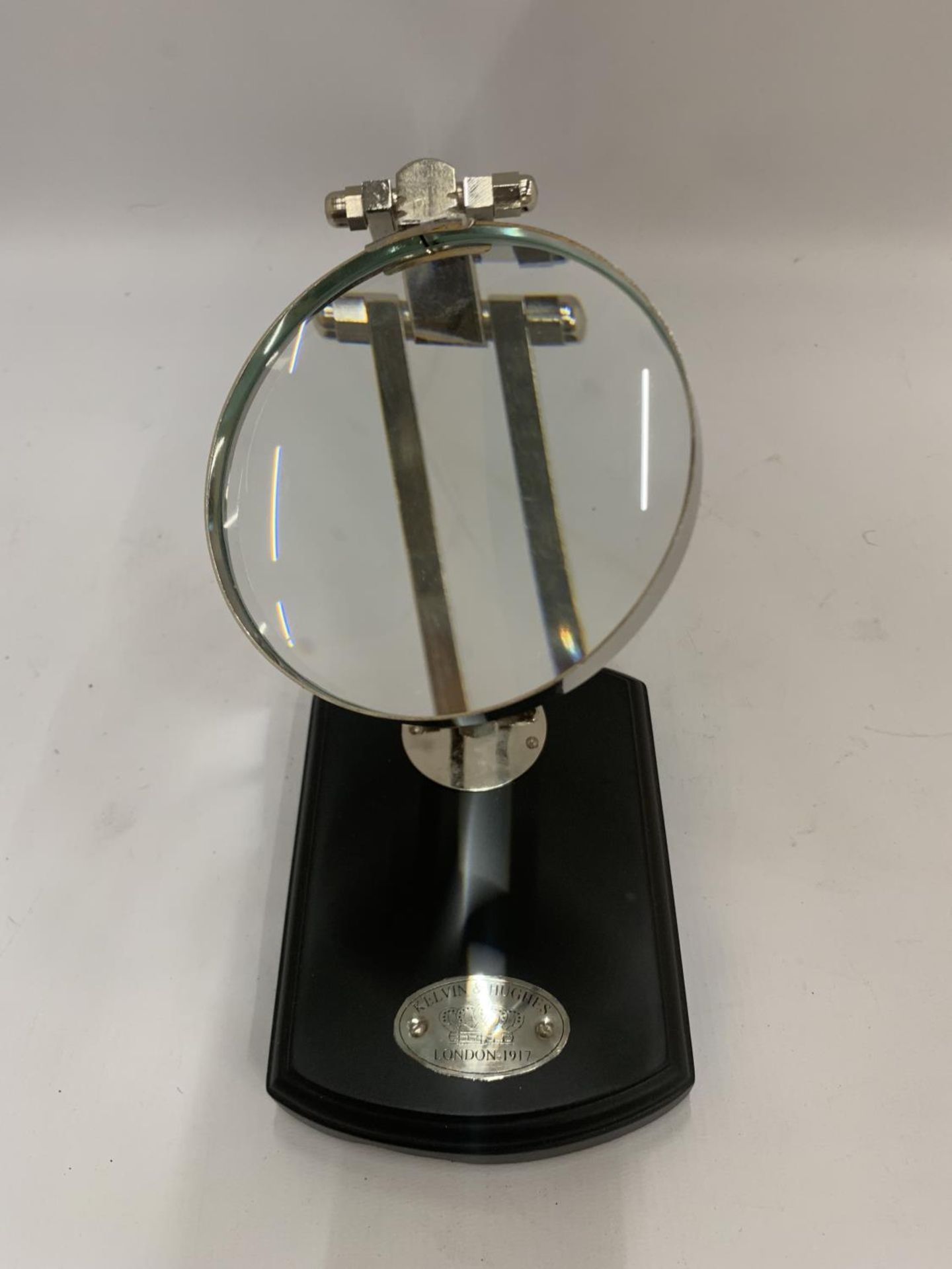 A BRASS MAGNIFYING GLASS ON A WOODEN BASE