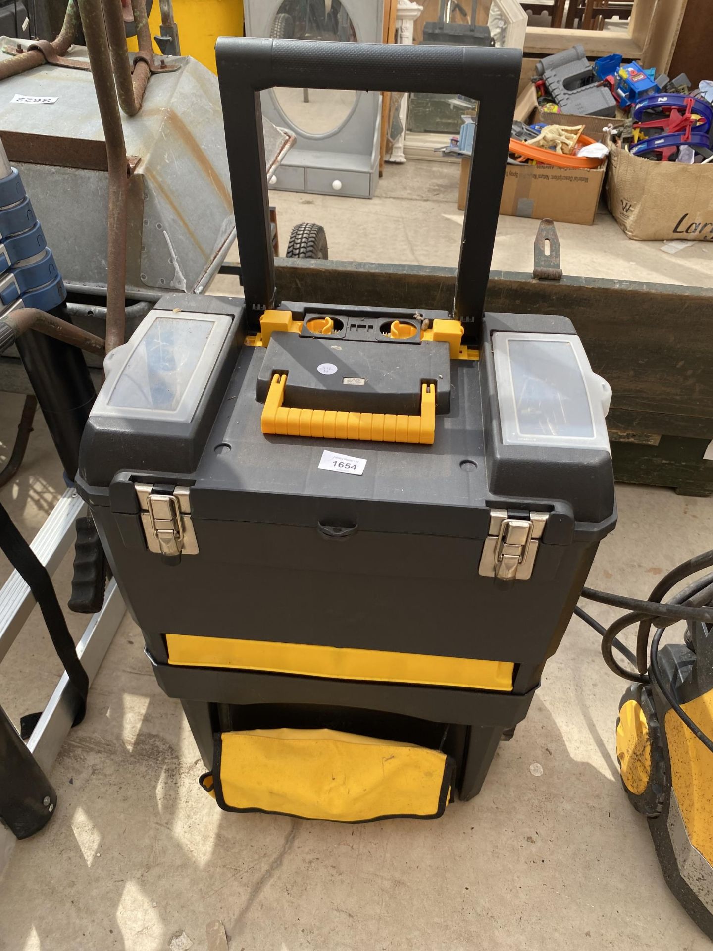 A PLASTIC TWO WHEELED TOOL BOX WITH AN ASSORTMENT OF TOOLS AND HARDWARE TO INCLUDE A WOOD PLANE