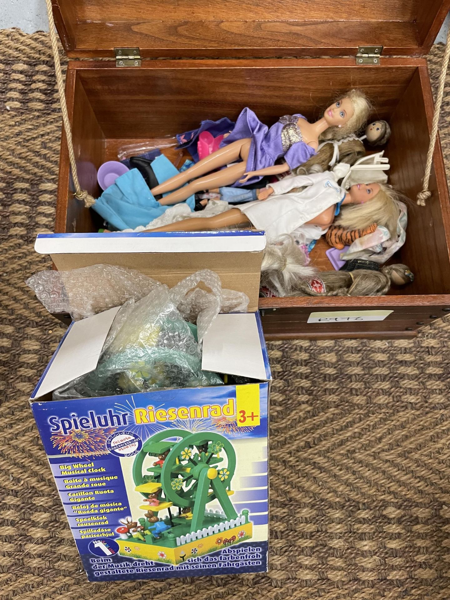 A WOODEN CHEST CONTAINING SEVERAL DOLLS AND CLOTHES INCLUDING THREE BARBIE DOLLS