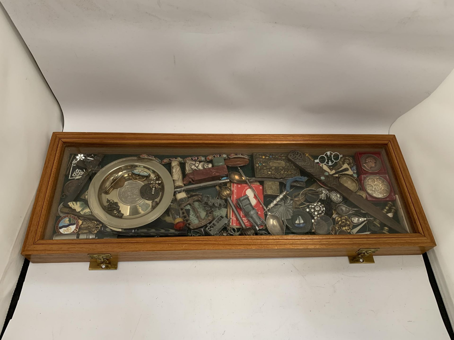 A WOODEN AND GLASS DISPLAY CASE OF ASSORTED COLLECTABLE ITEMS