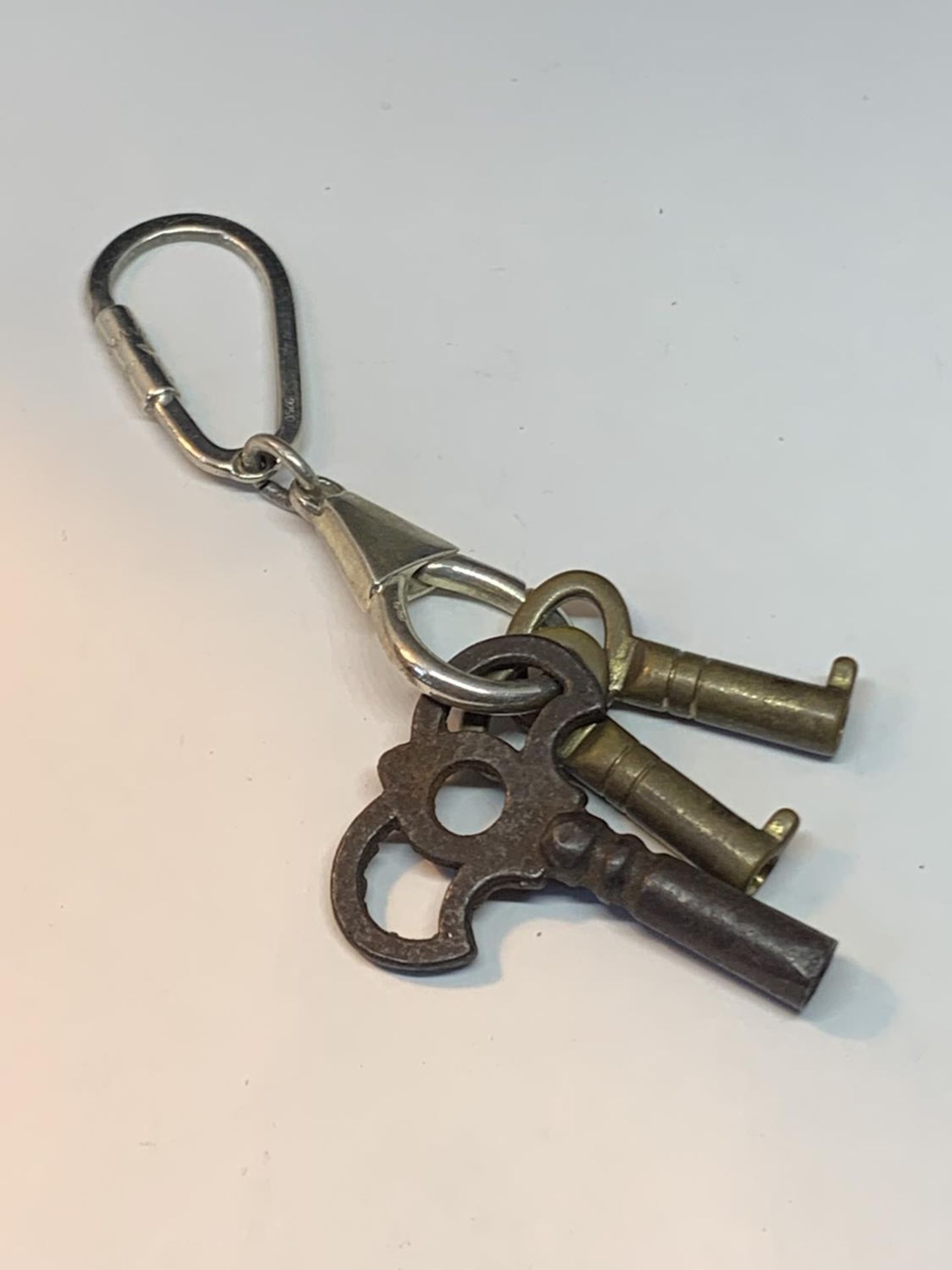 A SILVER KEYRING WITH THREE VINTAGE KEYS