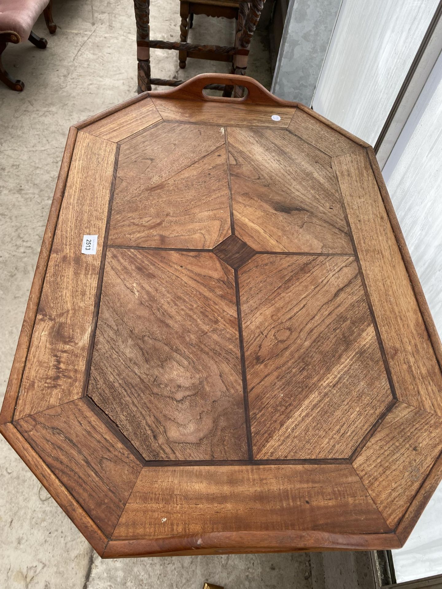 AN INDONESIAN HARDWOOD TWO HANDLED TRAY WITH CANTED CORNERS AND INSET TOP PANELS, ON TURNED X- - Image 3 of 4