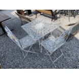 A DECORATIVE METAL BISTRO TABLE AND TWO FOLDING CHAIRS