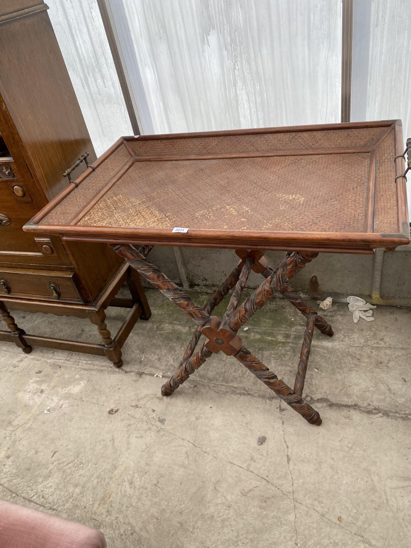 AN ORIENTAL HARDWOOD AND CANE TWO HANDLED TRAY ON HEAVILY CARVED X-FRAME STAND, 38X24"