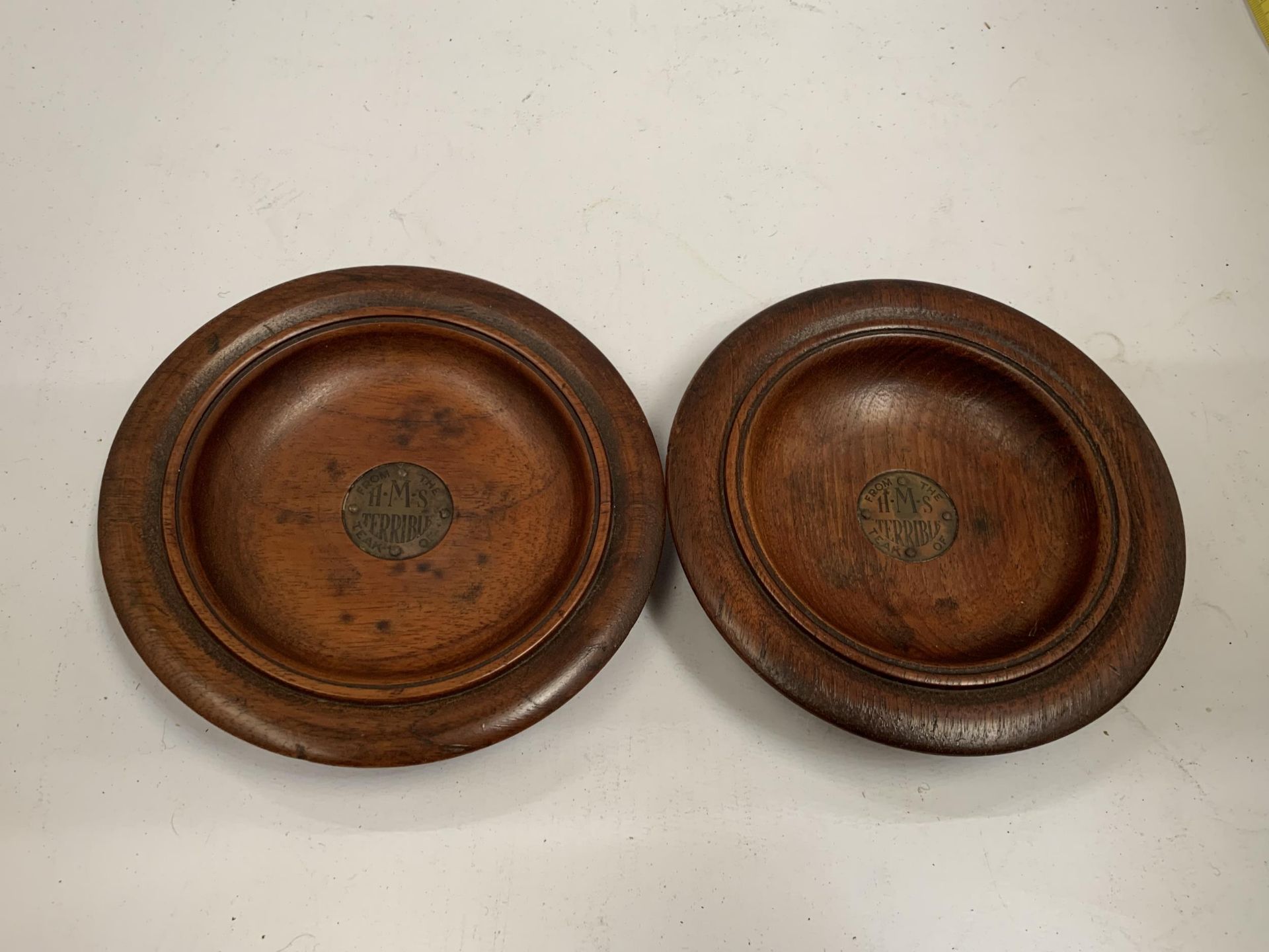 A PAIR OF TEAK FROM THE H.M.S TERRIBLE ASHTRAYS WITH METAL INSERT PLAQUES