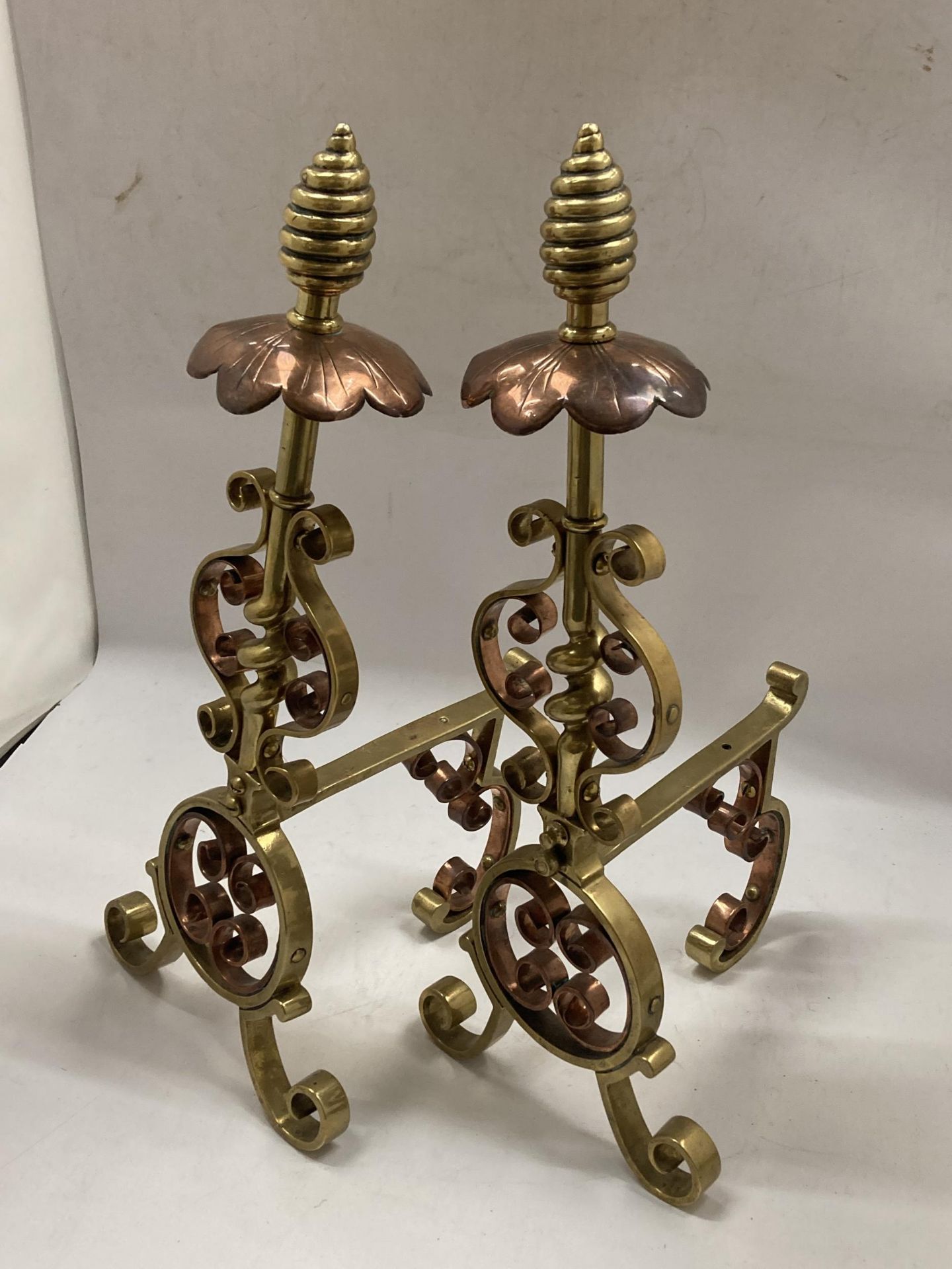 A PAIR OF BRASS AND COPPER ARTS AND CRAFTS FIRE DOGS