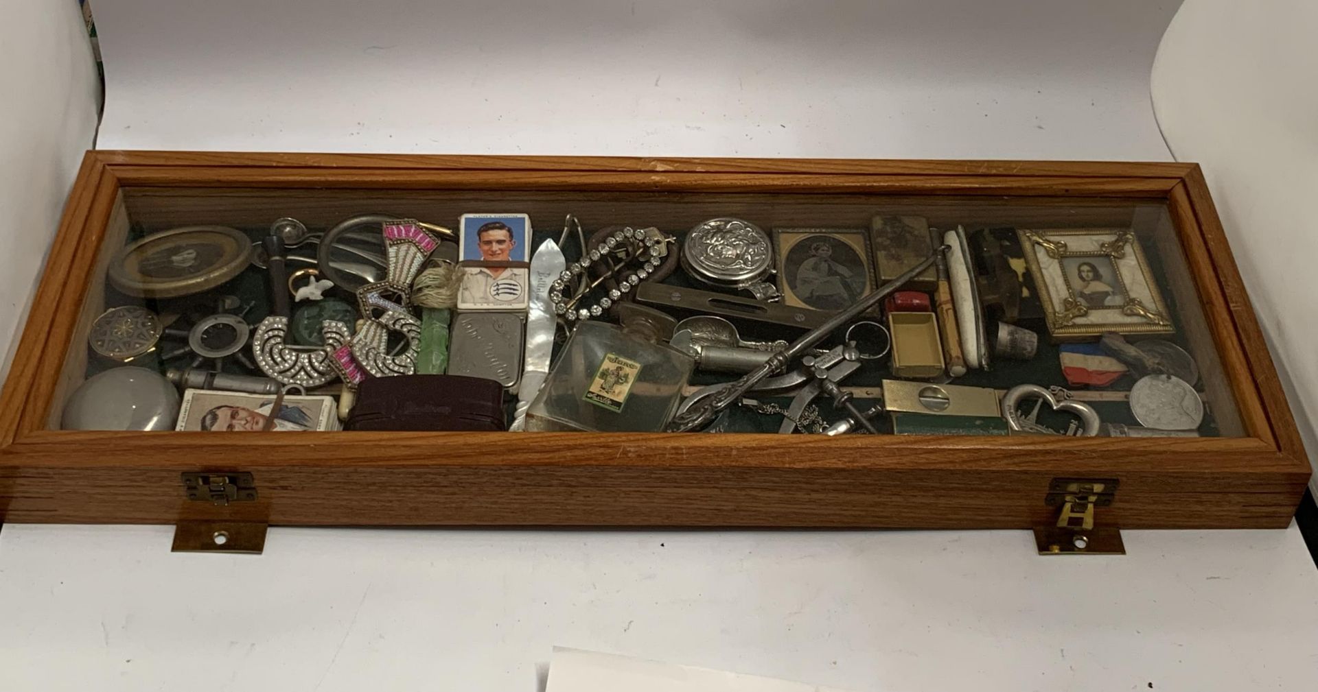 A GLASS AND WOODEN DISPLAY CASE CONTAINING ASSORTED COLLECTABLES