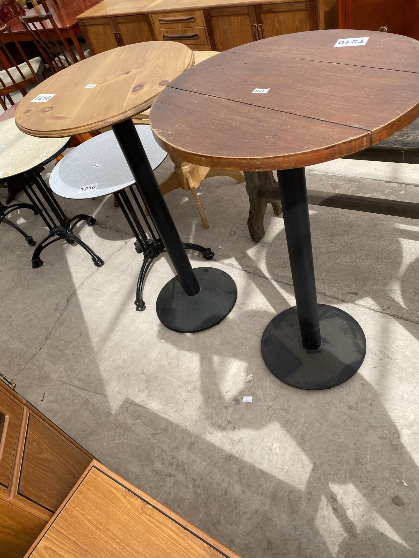 TWO TALL PUB TABLES, 24 AND 26" DIAMETER, ON BLACK METALWARE BASES