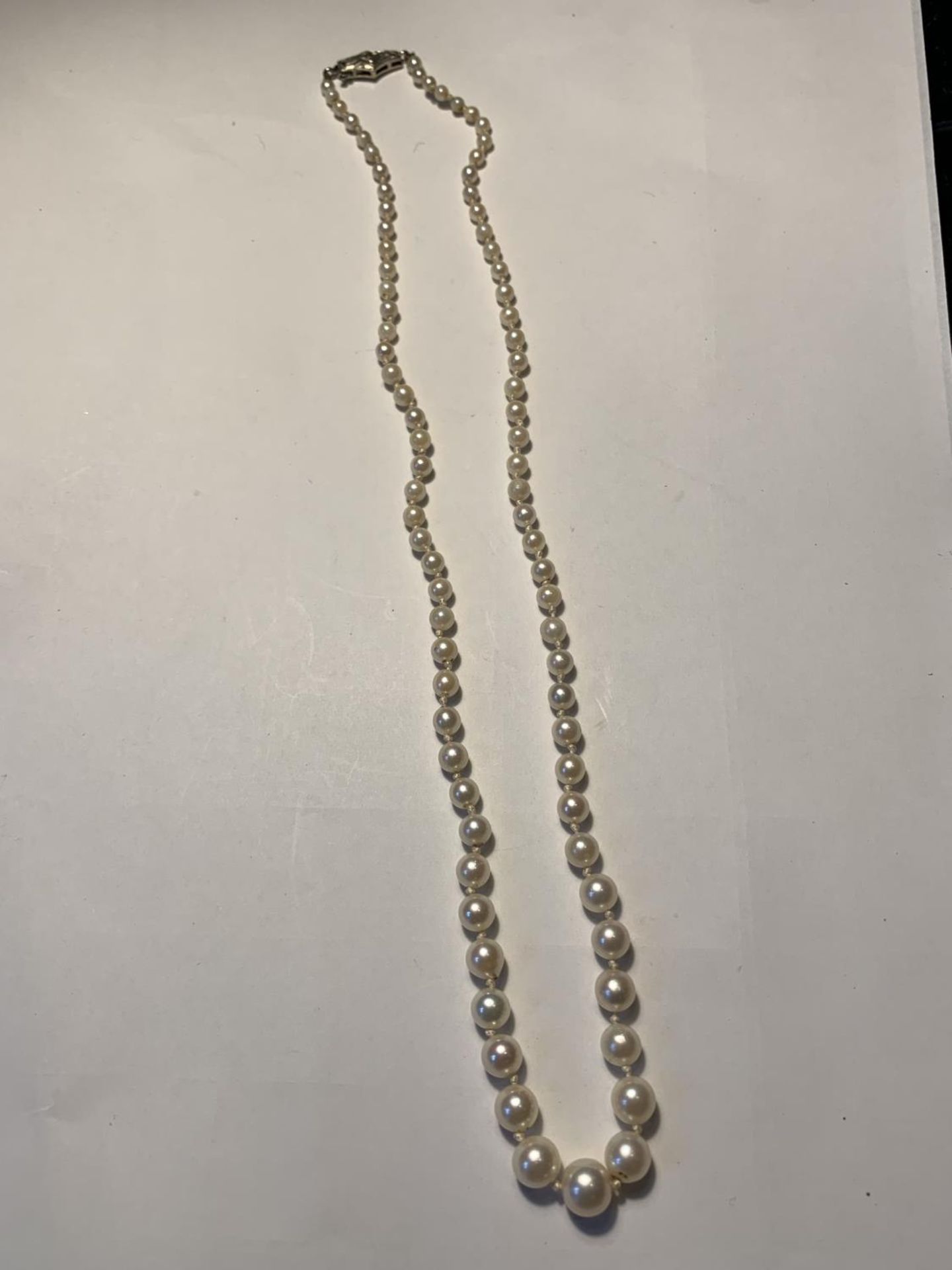 A STRING OF PEARLS WITH A 9 CARAT WHITE GOLD AND DIAMOND CLASP