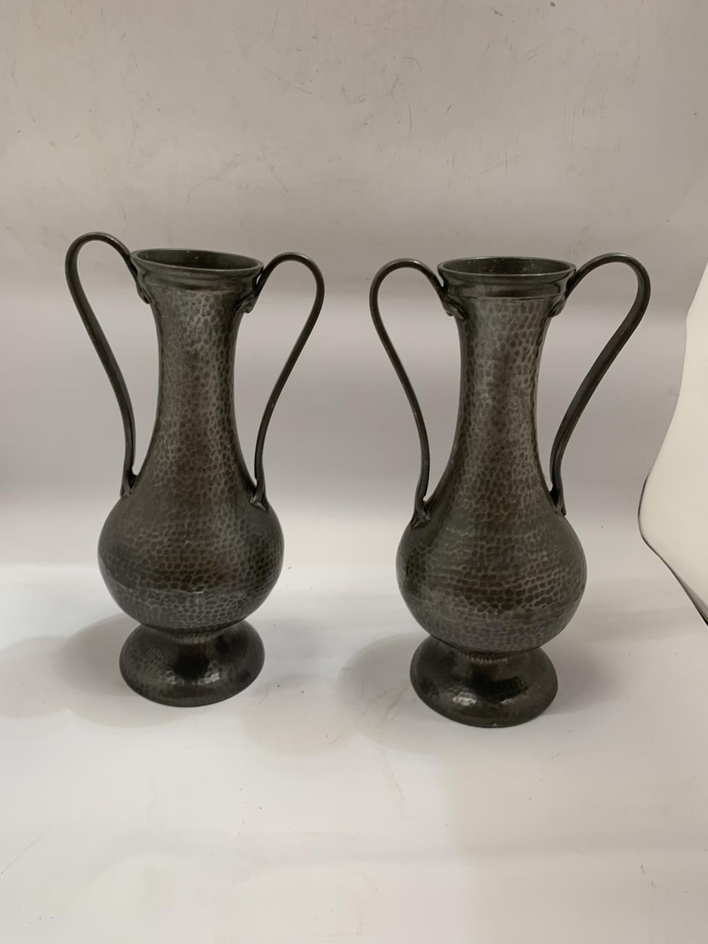 A PAIR OF ARTS AND CRAFTS STYLE TWIN HANDLED PEWTER VASES