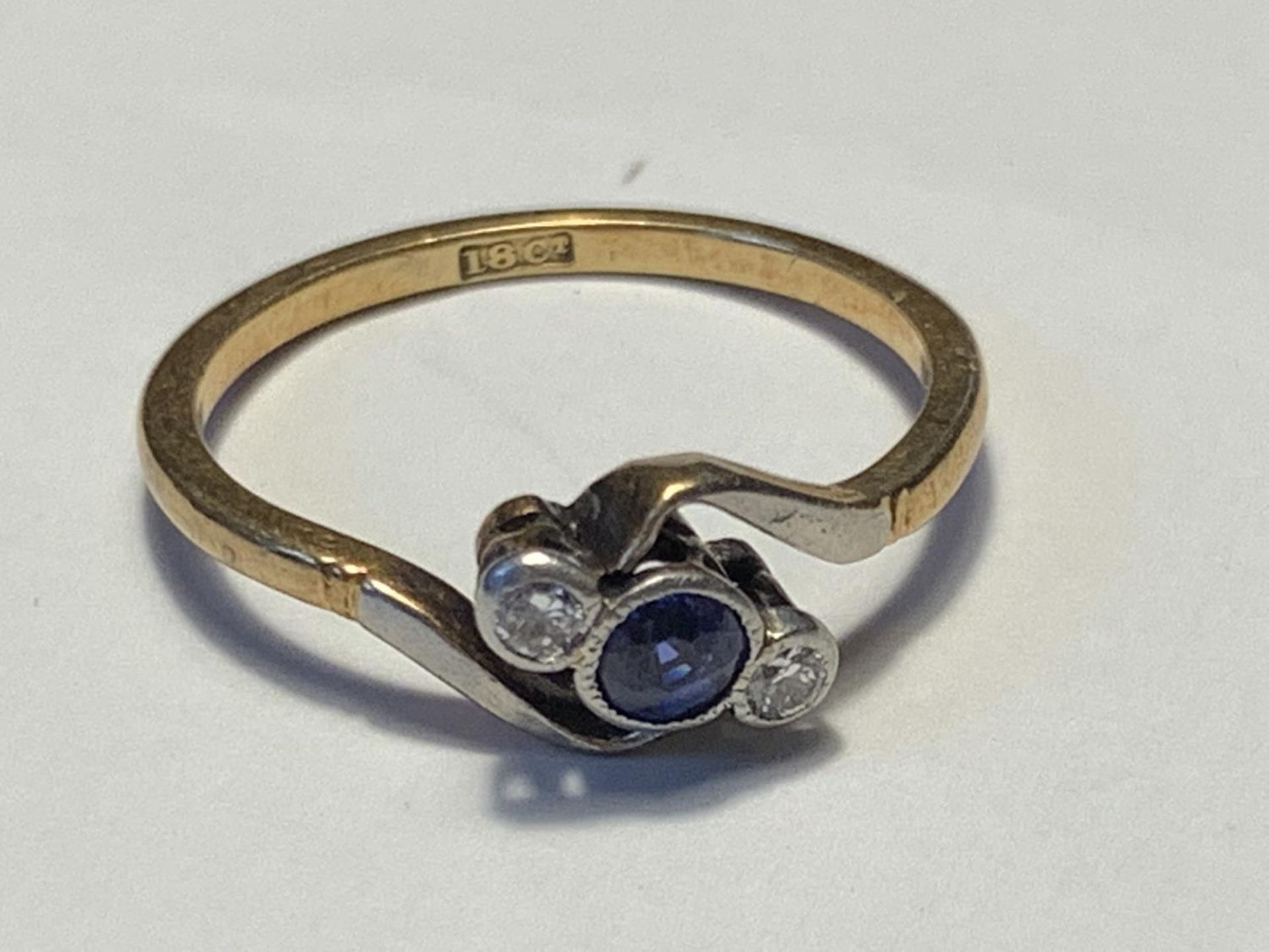 AN 18 CARAT GOD RING WITH A CENTRE SAPPHIRE AND A DIAMOND EACH SIDE ON A TWIST DESIGN SIZE K/L GROSS