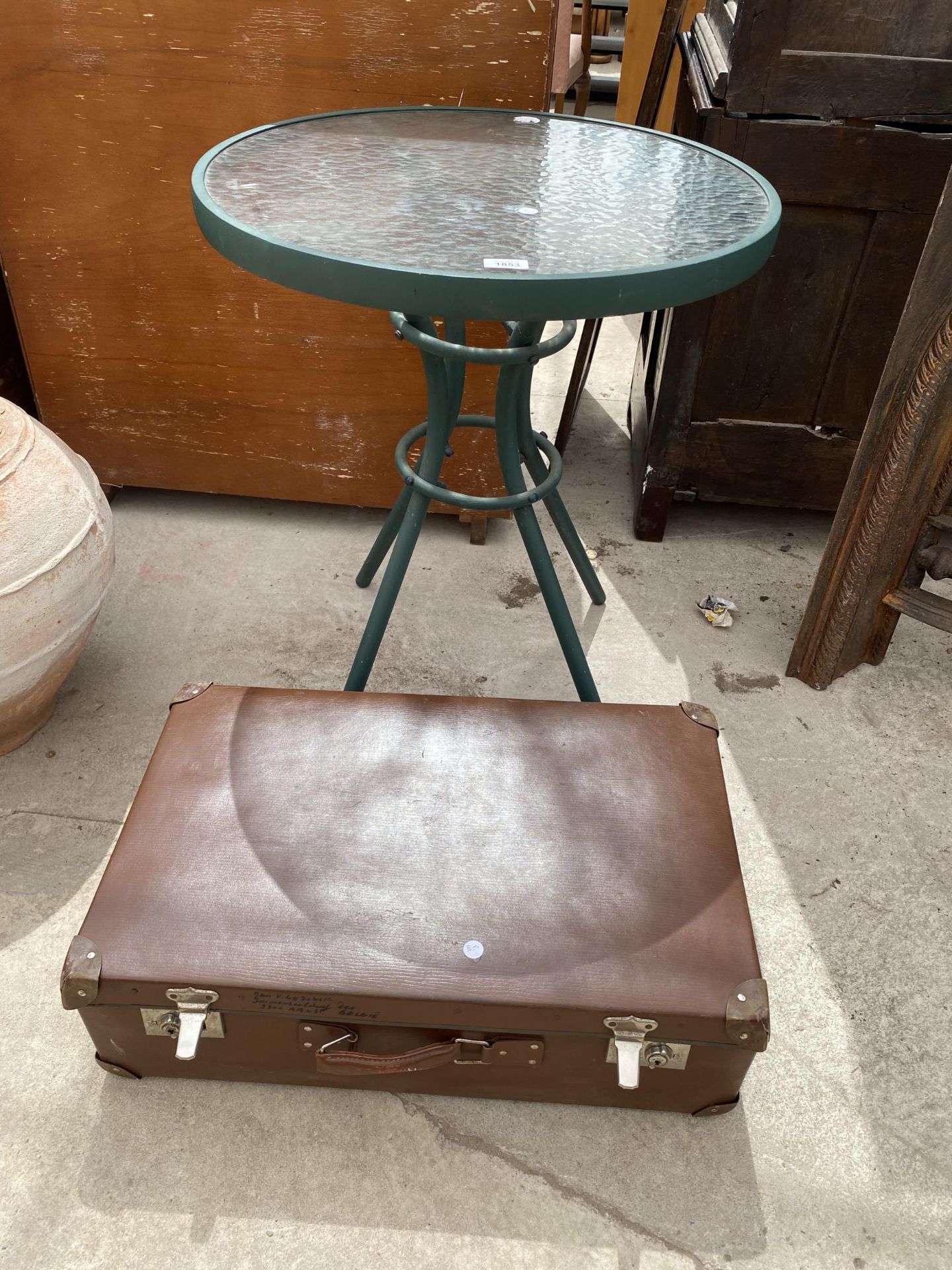 A GLASS TOPPED BISTRO TABLE AND A TRAVEL CASE