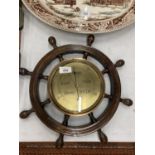 A BRASS FACED BAROMETER IN A WOODEN SHIPS WHEEL