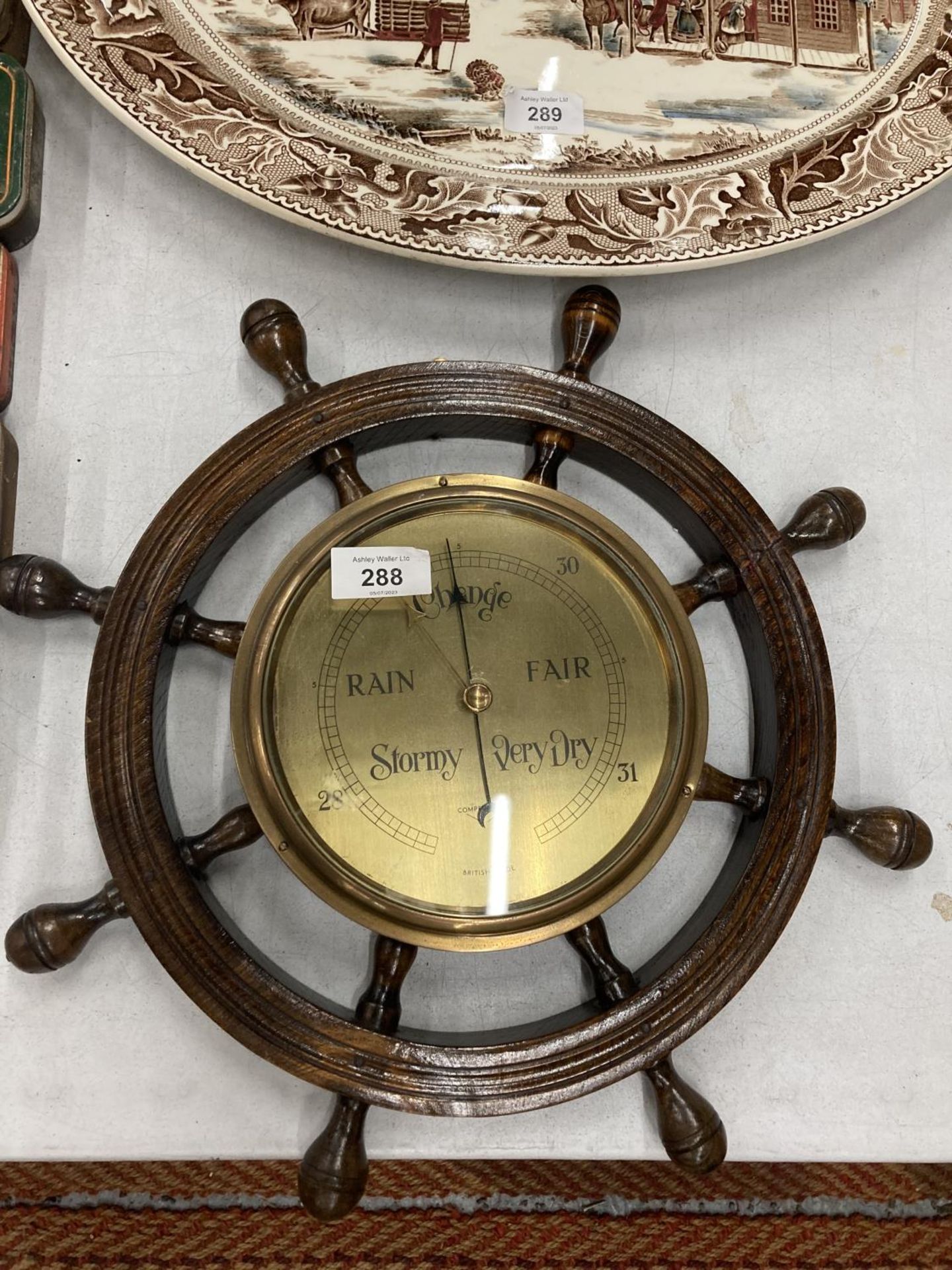A BRASS FACED BAROMETER IN A WOODEN SHIPS WHEEL