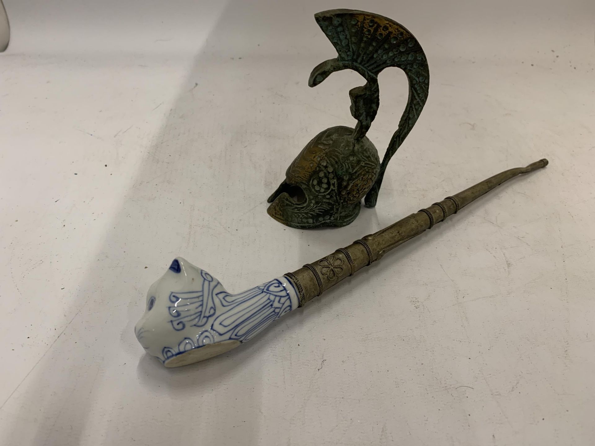 A VINTAGE TOBACCO SMOKING PIPE WITH CERAMIC CAT HEAD PLUS A BRONZE STYLE ROMAN HELMET BELL