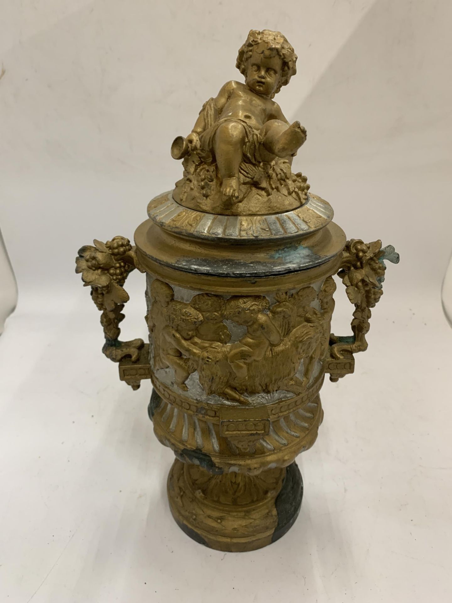 A 19TH CENTURY PEDESTAL URN WITH NEO-CLASSICAL RELIEF DESIGN ON FLUTED BASE WITH CHERUB FIGURAL LID,