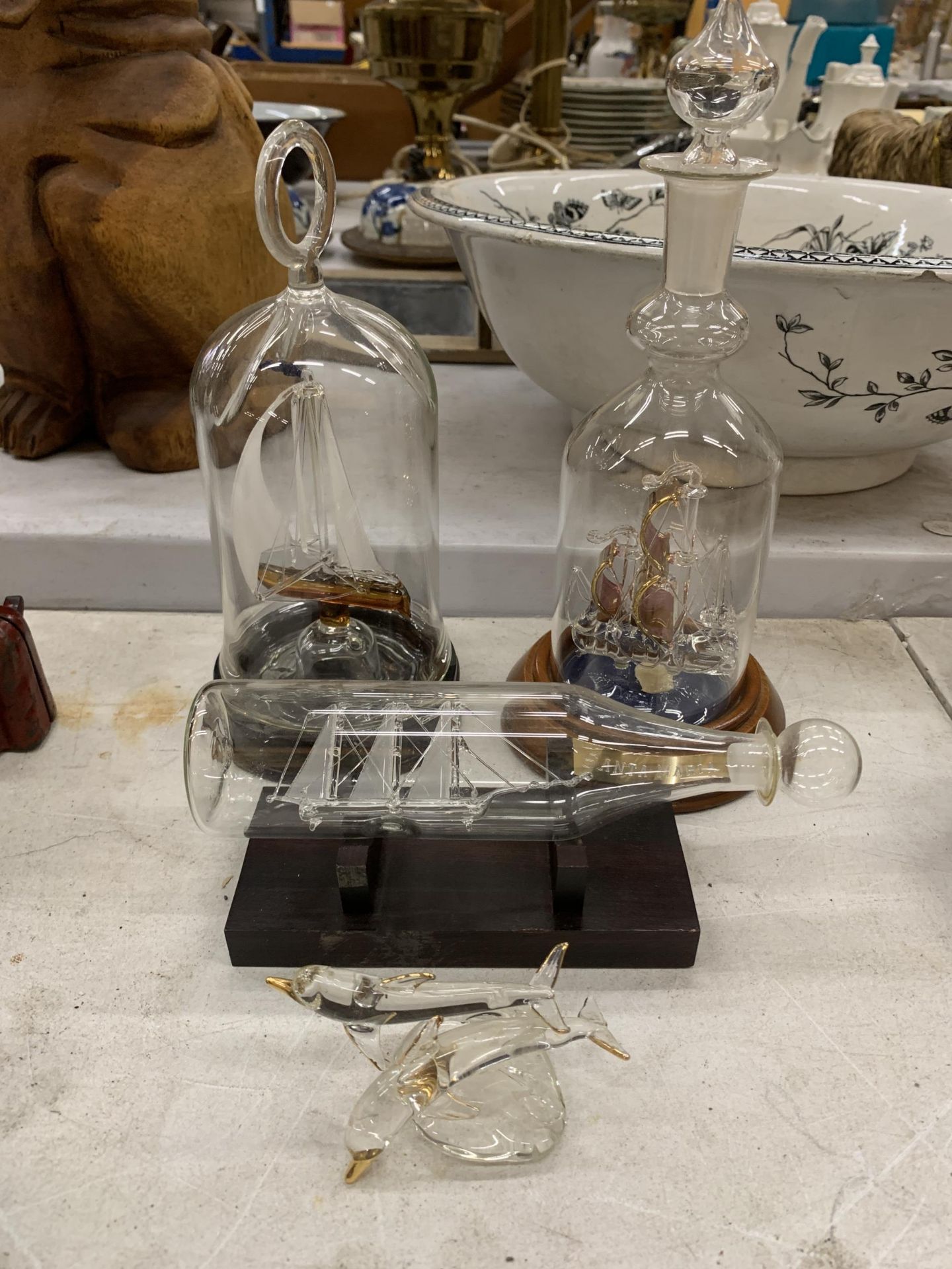 THREE GLASS SHIPS IN BOTTLES ON WOODEN BASES PLUS A GLASS DOLPHIN FIGURE
