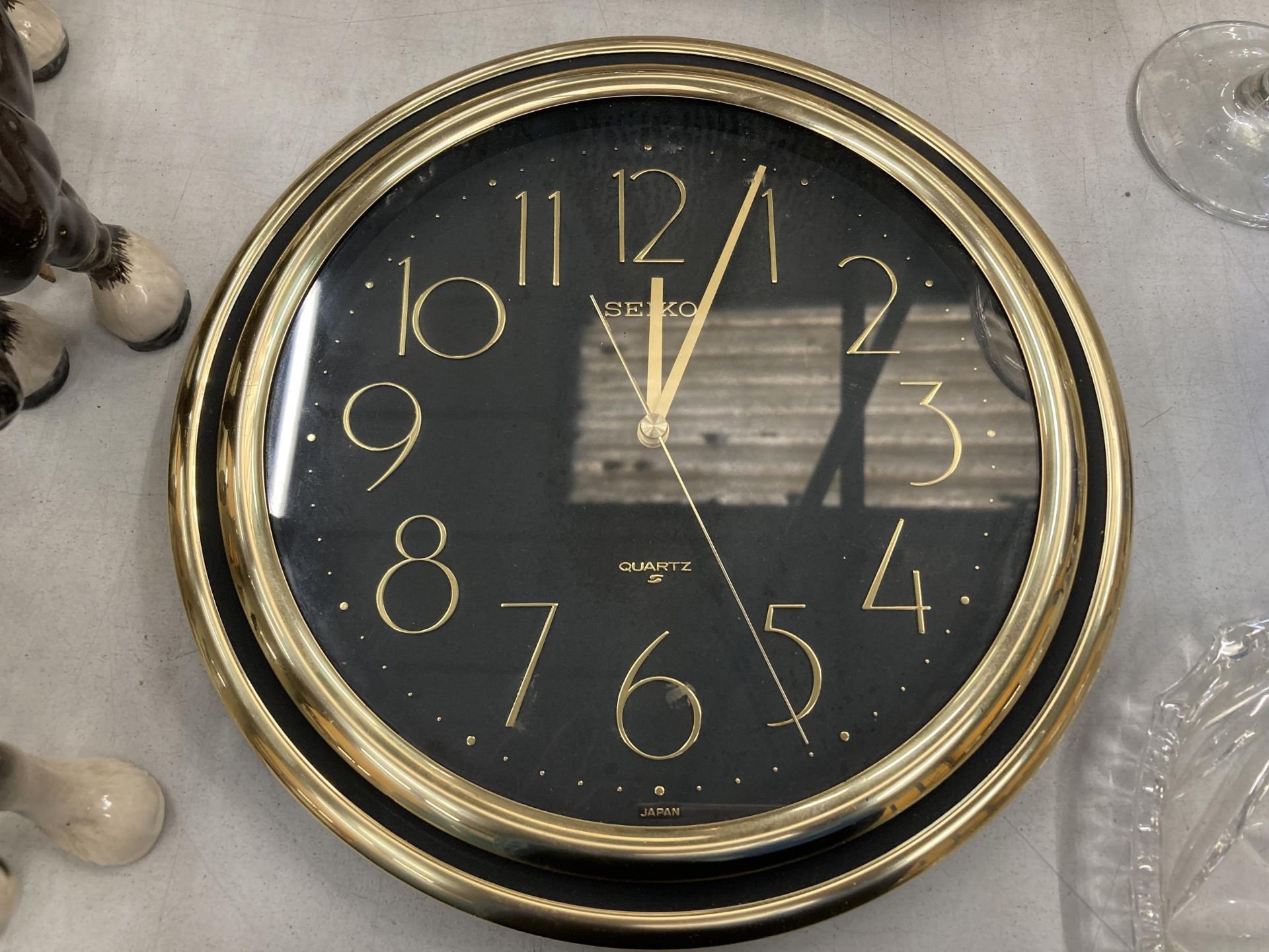 A SEIKO BLACK AND GOLD COLOURED WALL CLOCK - WORKING AT TIME OF CATALOGUING