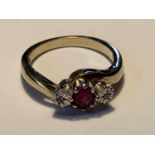 A 9 CARAT GOLD RING WITH A CENTRE RUBY AND A DIAMOND EACH SIDE SIZE L