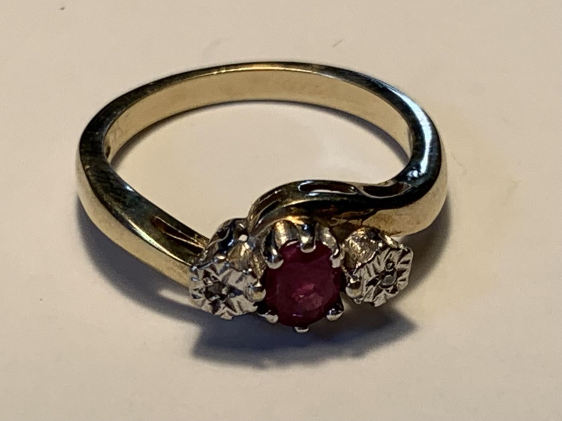 A 9 CARAT GOLD RING WITH A CENTRE RUBY AND A DIAMOND EACH SIDE SIZE L