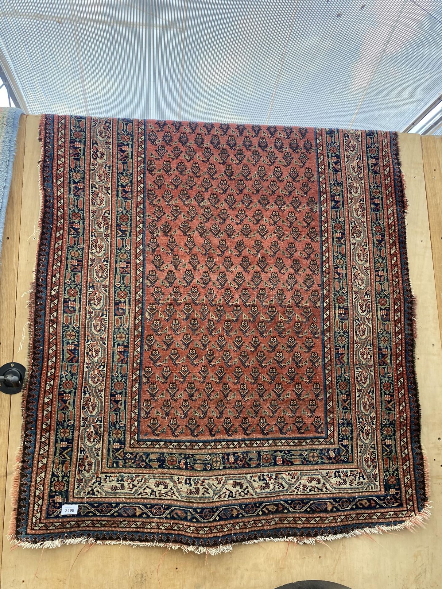 A VINTAGE RED PATTERNED FRINGED RUG