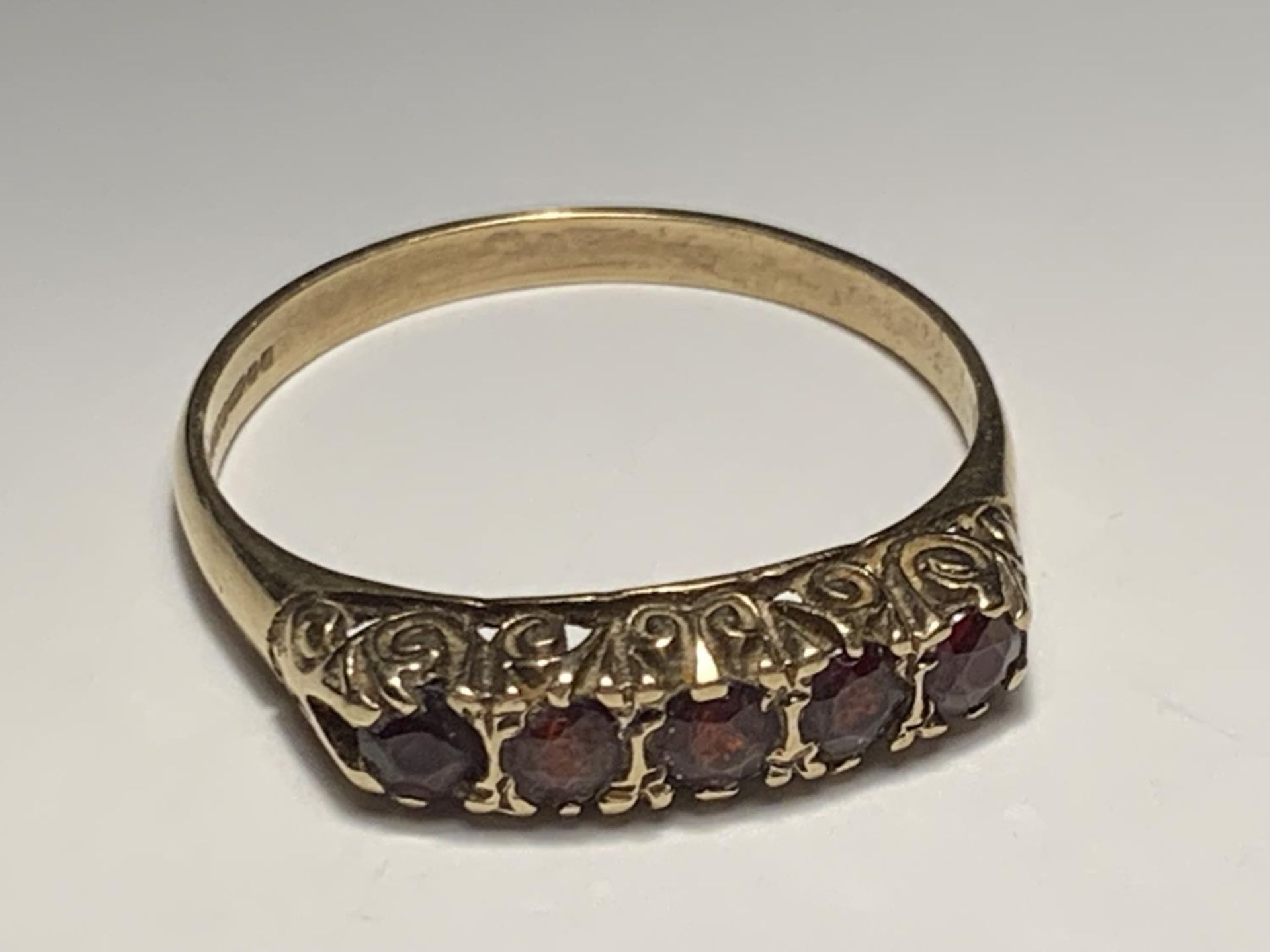 A 9 CARAT GOLD RING WITH FIVE IN LINE GARNETS SIZE T